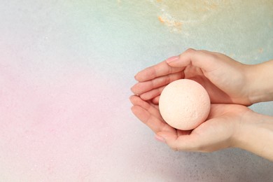 Woman holding bath bomb over water with foam, top view. Space for text