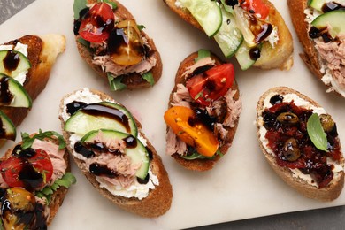 Photo of Delicious bruschettas with balsamic vinegar and different toppings on grey table, top view