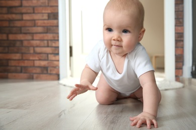 Cute little baby crawling on floor indoors, space for text