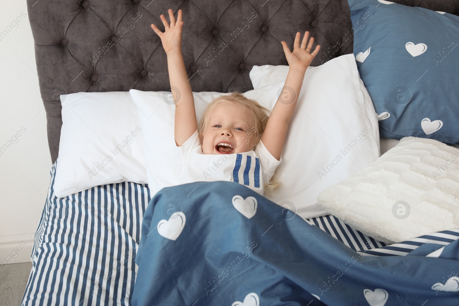 Photo of Cute little girl stretching after sleeping in bed at home