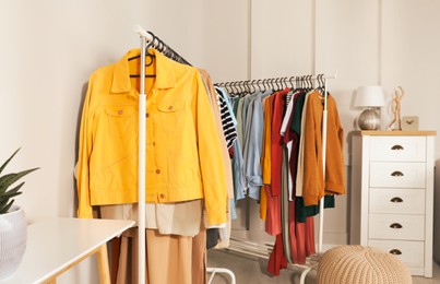 Racks with stylish clothes in cozy room interior. Fast fashion