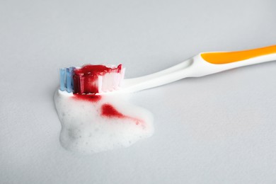 Photo of Toothbrush with paste and blood on white background, closeup. Gum inflammation