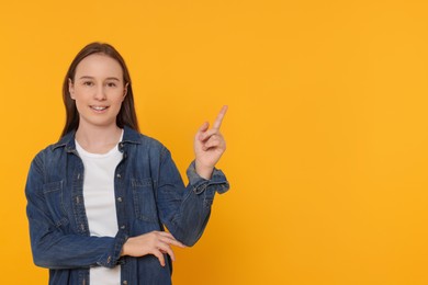 Photo of Portrait of teenage girl on orange background. Space for text