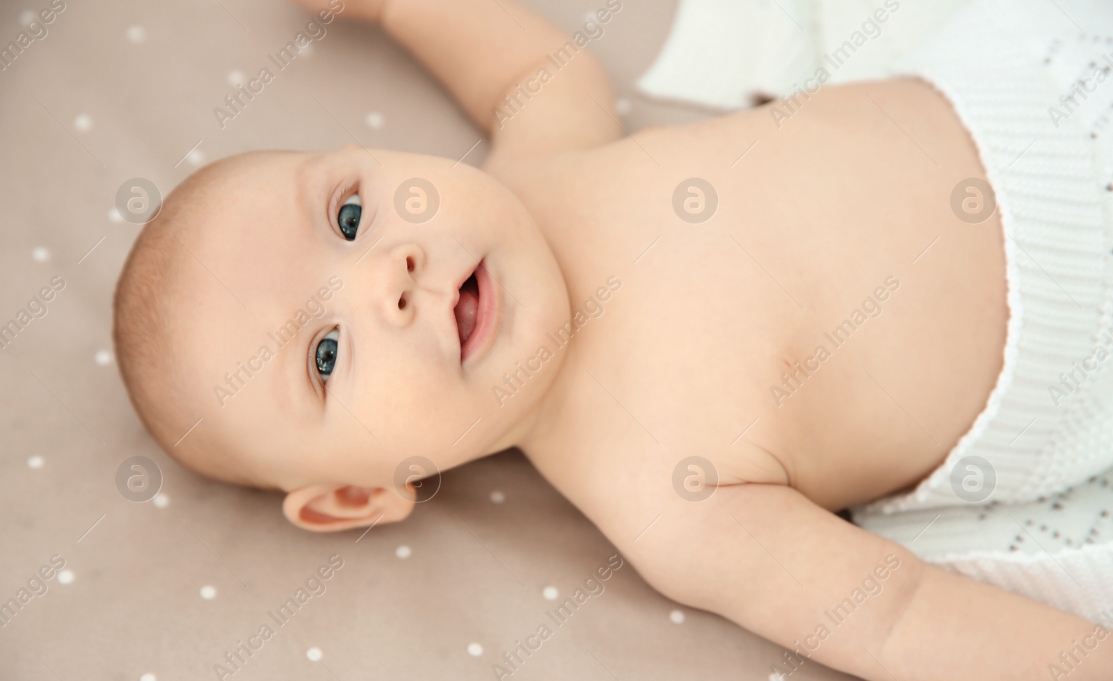 Photo of Adorable baby girl lying in bed, top view