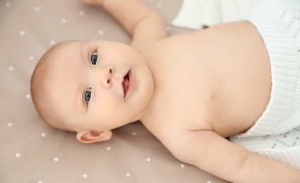 Adorable baby girl lying in bed, top view