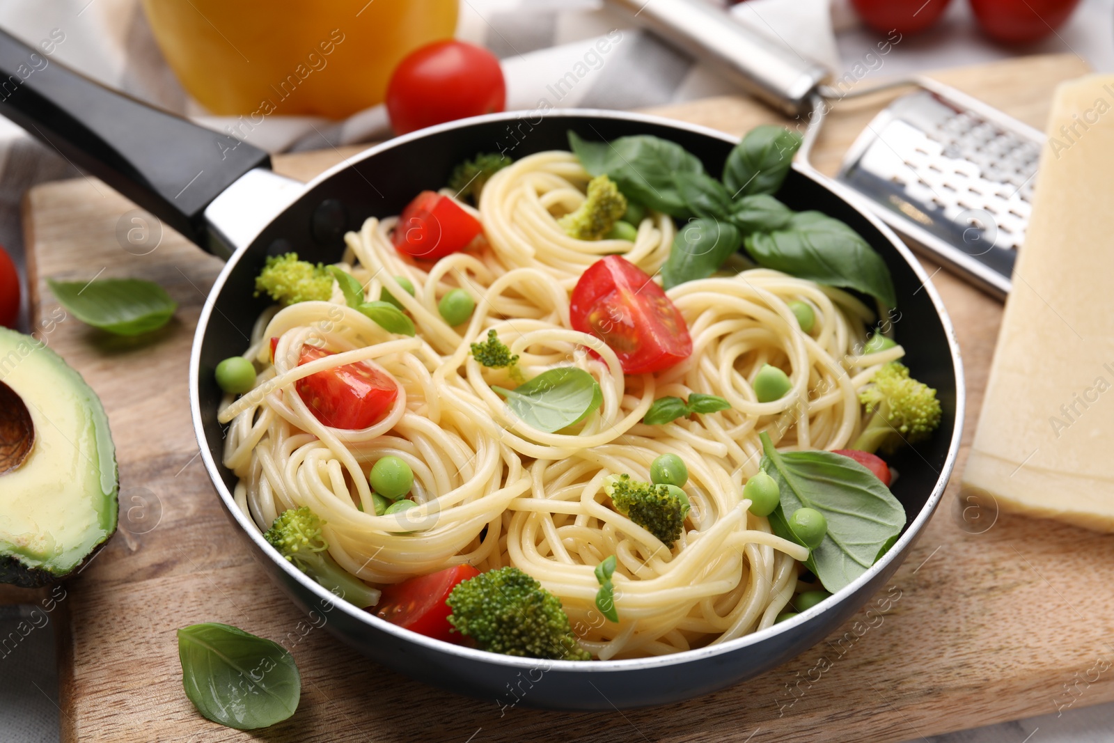 Photo of Delicious pasta primavera in frying pan and ingredients on table, closeup