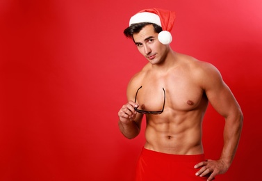 Sexy shirtless Santa Claus on red background, space for text