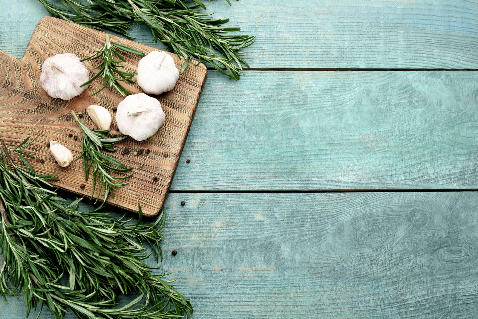 Photo of Fresh rosemary, garlic and pepper on light blue wooden table, flat lay. Space for text