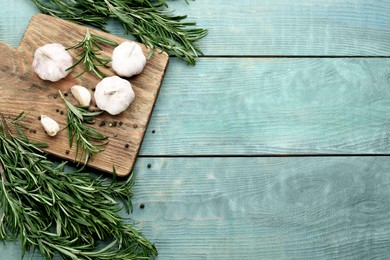 Fresh rosemary, garlic and pepper on light blue wooden table, flat lay. Space for text