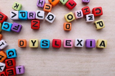 Colorful beads with word Dyslexia on light table, flat lay