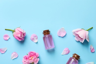 Photo of Fresh flowers, petals and bottles of rose essential oil on color background, flat lay. Space for text