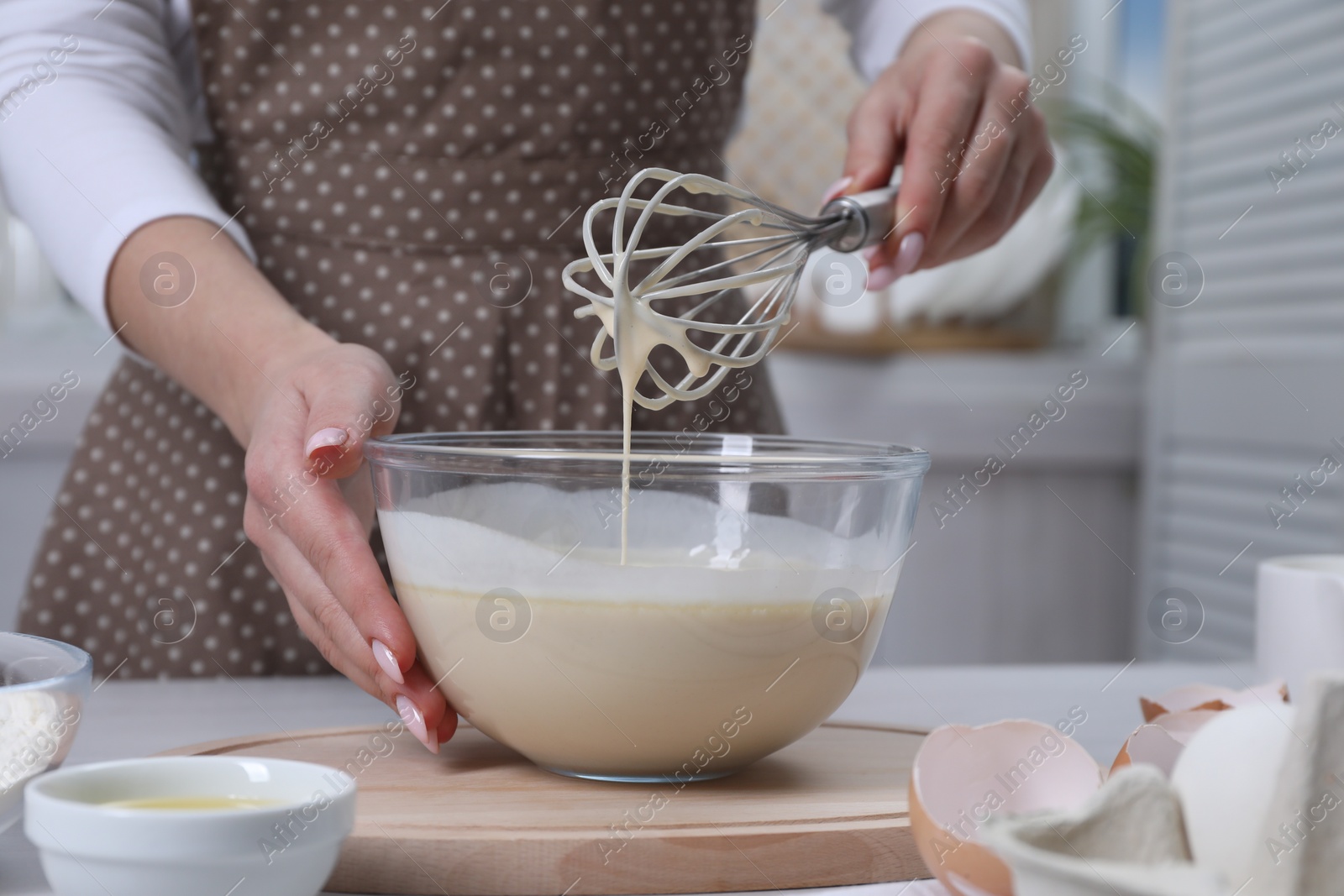 Photo of Woman making dough with whisk in bowl at table, closeup