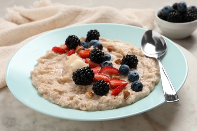 Photo of Tasty oatmeal porridge with berries and almond nuts in plate on table