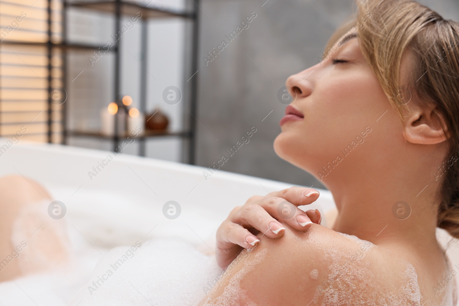 Photo of Beautiful woman taking bath with foam in tub indoors. Space for text