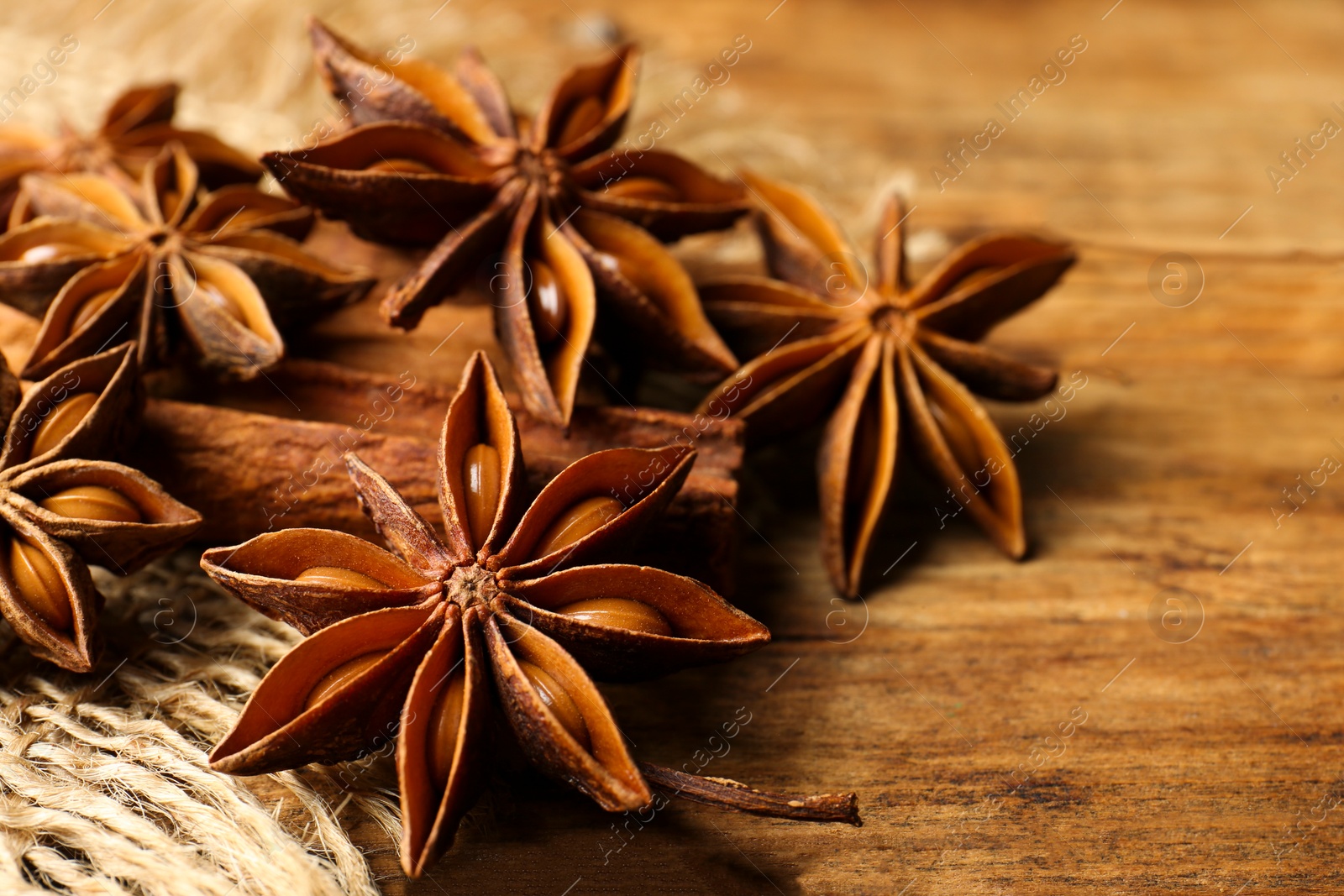 Photo of Aromatic anise stars and cinnamon sticks on wooden table, closeup