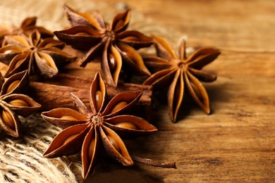 Photo of Aromatic anise stars and cinnamon sticks on wooden table, closeup