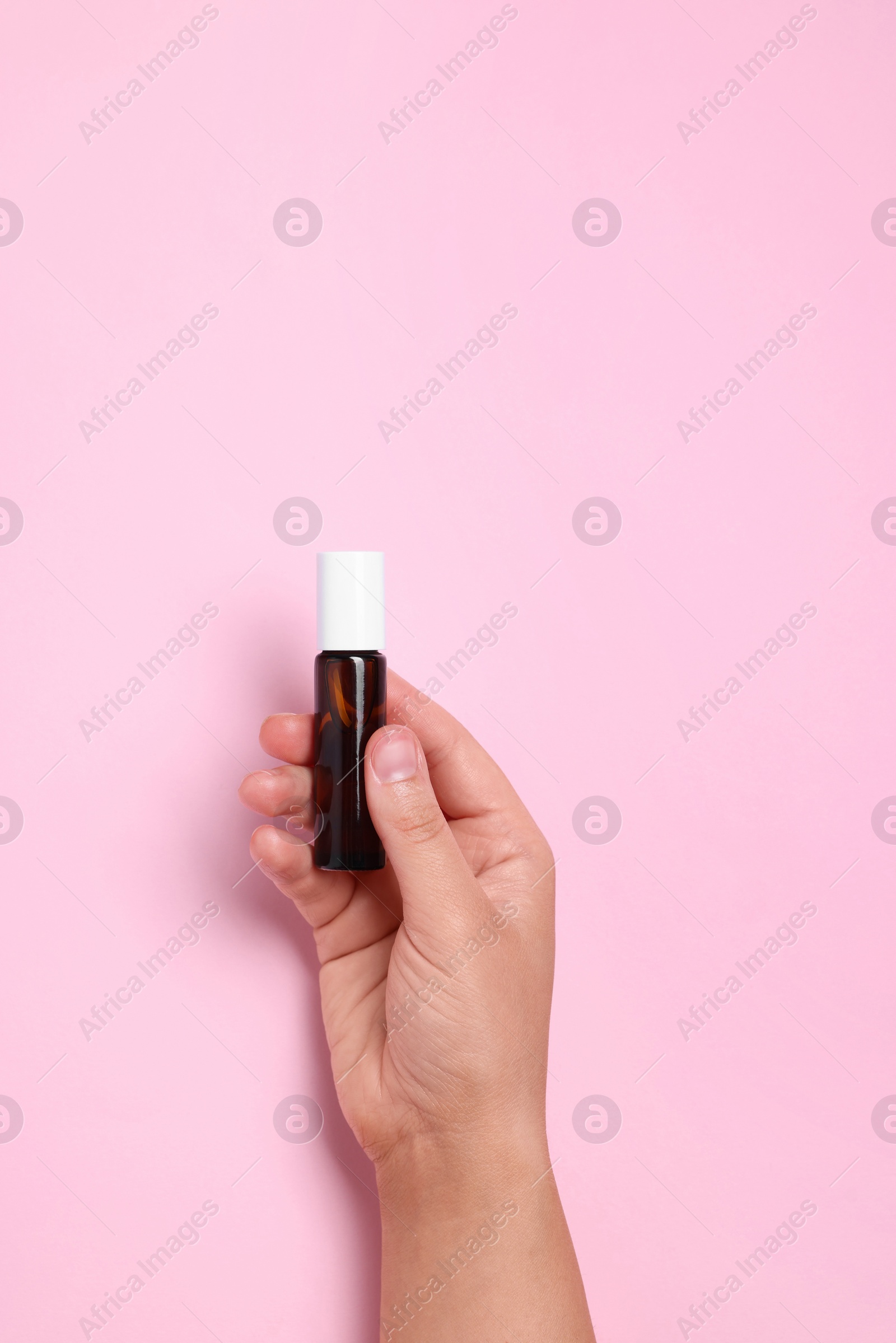 Photo of Woman with bottle of essential oil on pink background, closeup. Space for text