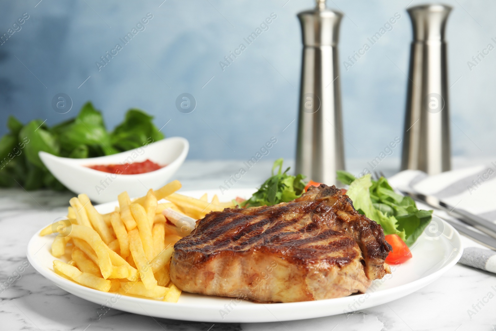 Photo of Tasty grilled beef steak, French fries and salad on white marble table