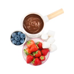 Photo of Fondue pot with melted chocolate, fresh berries and marshmallows isolated on white, top view