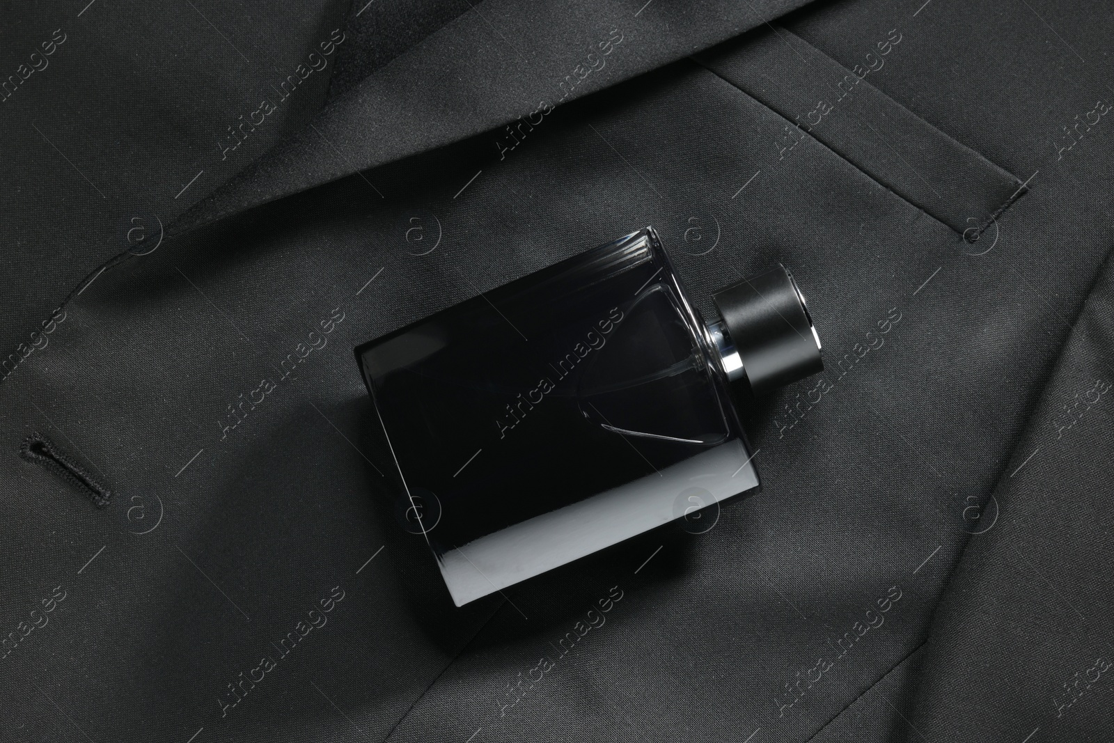 Photo of Luxury men's perfume in bottle on black jacket, top view