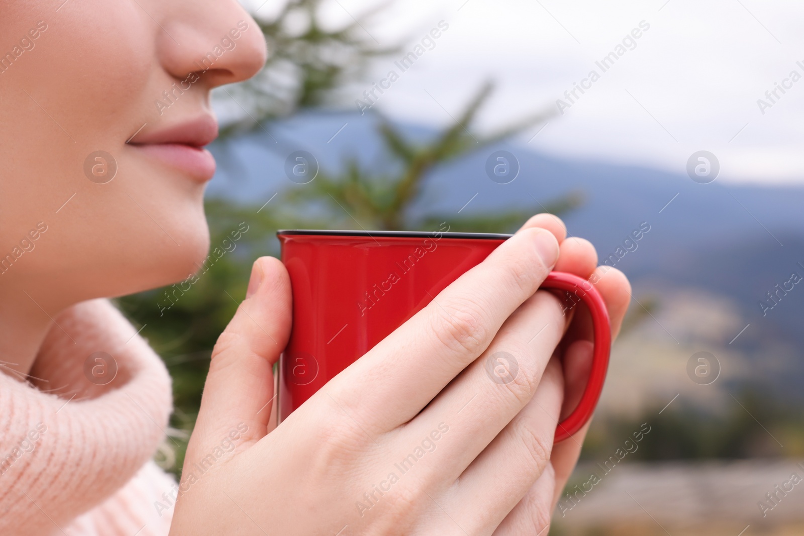 Photo of Young woman with mug of hot drink in mountains, closeup