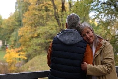 Photo of Portrait of affectionate senior couple in autumn park, space for text