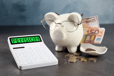 Image of Calculator with word Pension, broken piggy bank and money on grey background, closeup