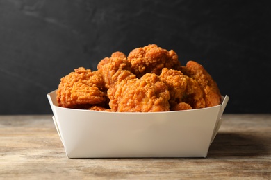 Photo of Tasty deep fried chicken pieces on wooden table