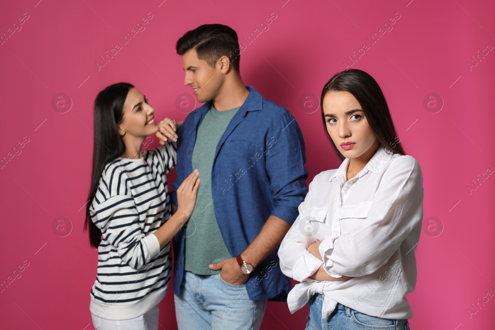 Photo of Unhappy woman feeling jealous while couple spending time together on pink background