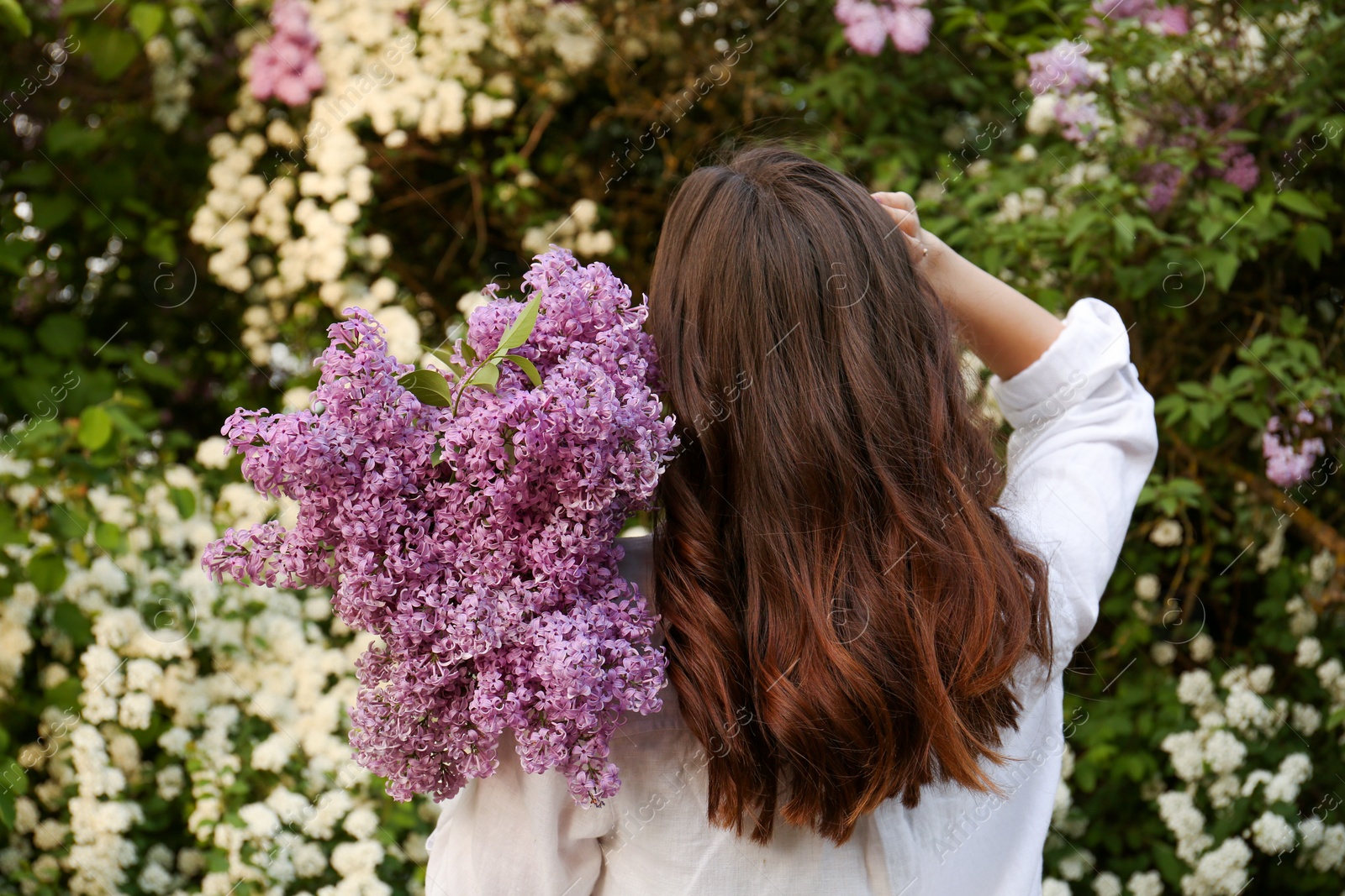 Photo of Woman with lilac flowers outdoors, back view