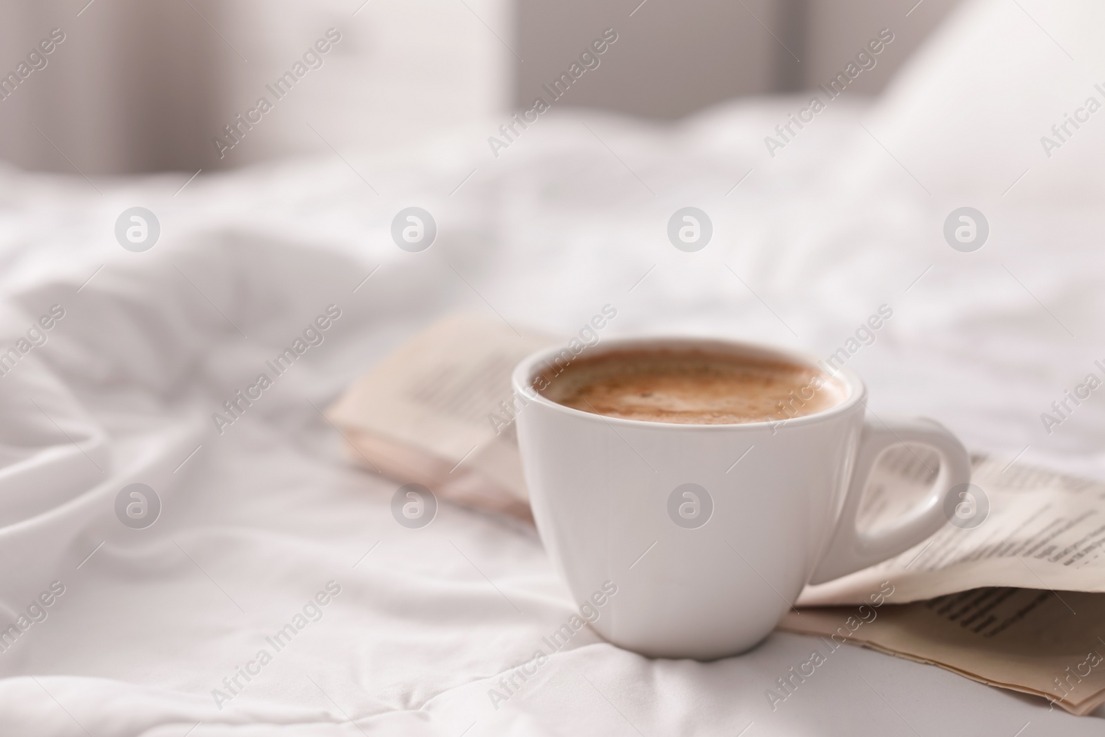 Photo of Morning coffee and newspaper on bed. Space for text