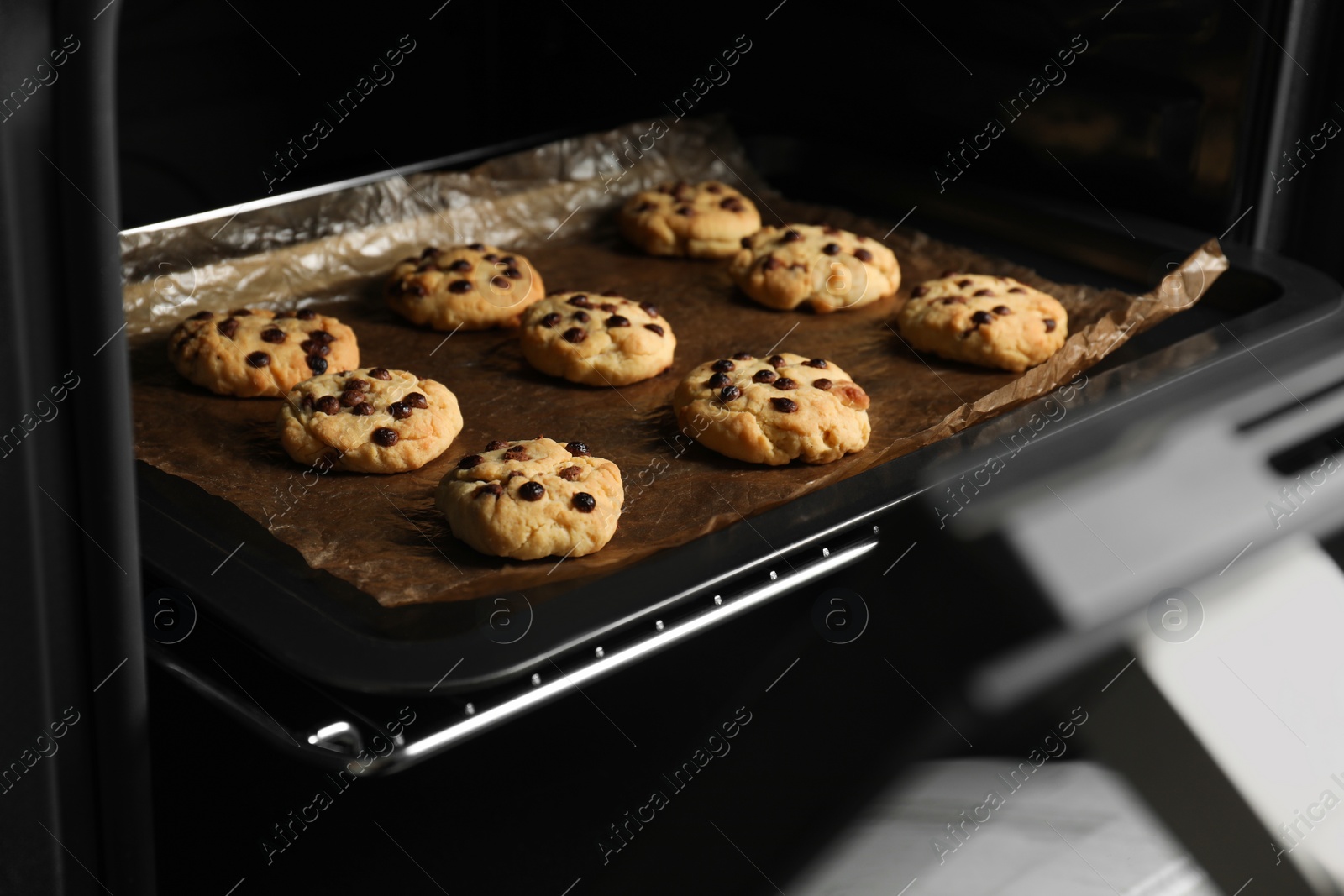 Photo of Baking delicious chocolate chip cookies in oven, closeup