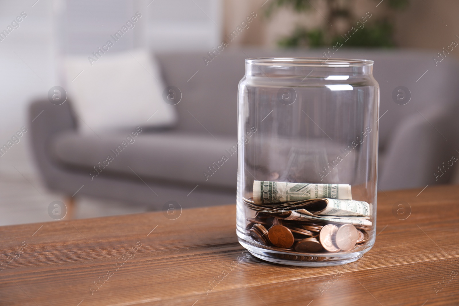 Photo of Donation jar with money on table against blurred background. Space for text