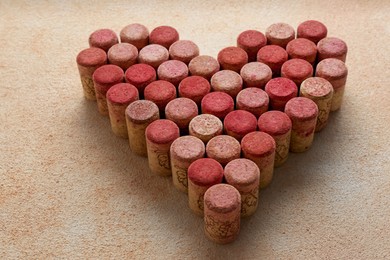 Photo of Heart made of wine bottle corks on textured table, closeup