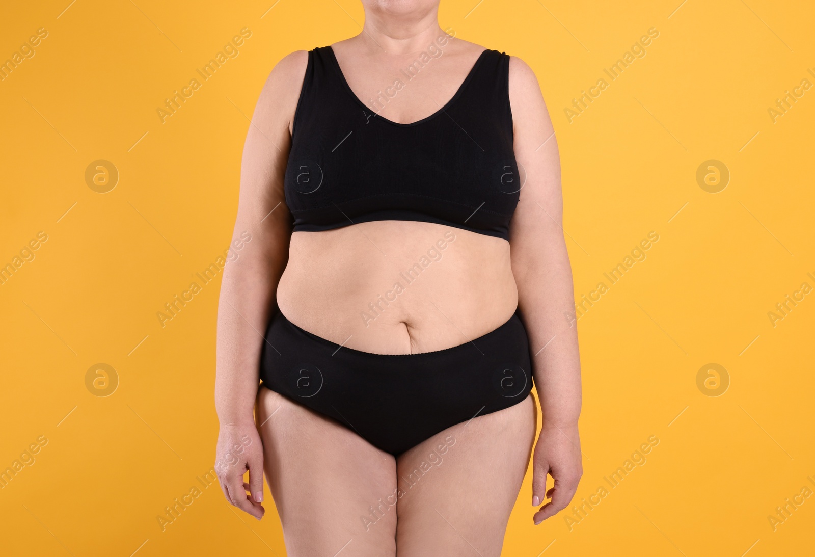 Photo of Overweight woman in underwear on orange background, closeup