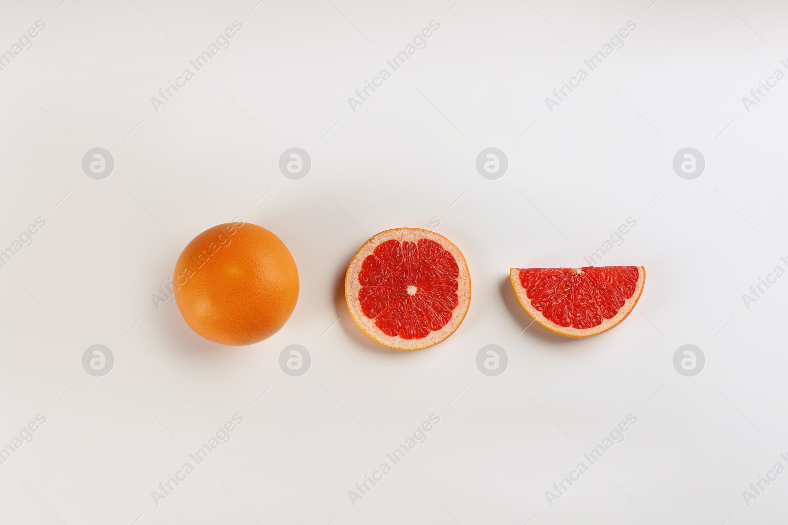 Photo of Cut and whole ripe grapefruits on white background, flat lay