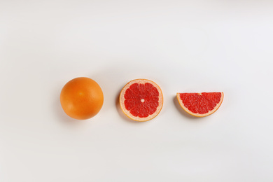 Cut and whole ripe grapefruits on white background, flat lay