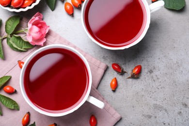 Photo of Fresh rose hip tea and berries on grey table, flat lay