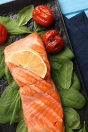 Photo of Tasty grilled salmon with tomatoes, spinach and lemon on table, top view