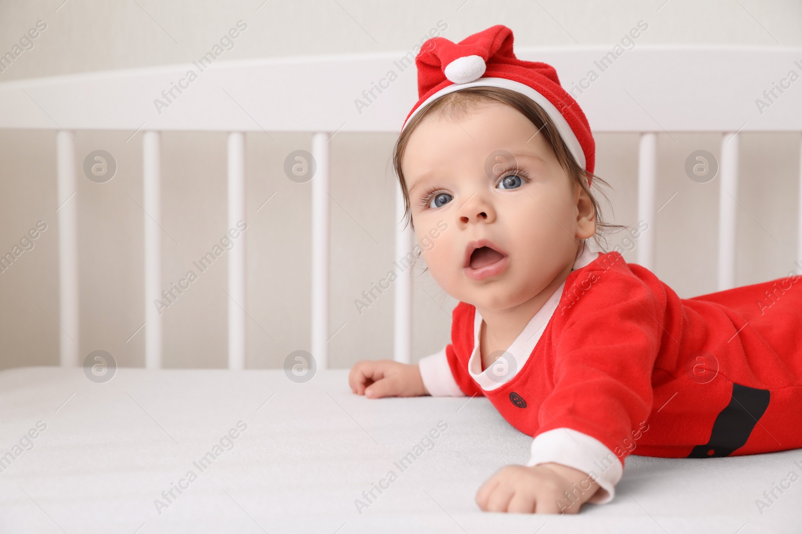 Photo of Cute baby wearing festive Christmas costume in crib. Space for text