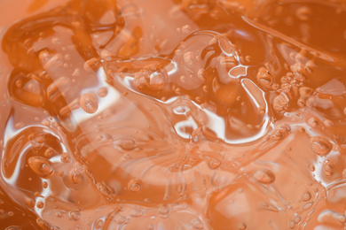 Photo of Pure transparent cosmetic gel on orange background, closeup