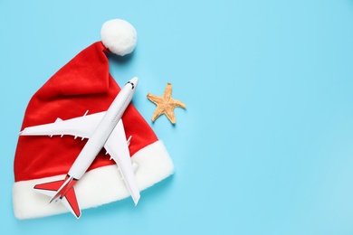 Photo of Santa hat with toy airplane, starfish and space for text on light blue background, flat lay. Christmas vacation