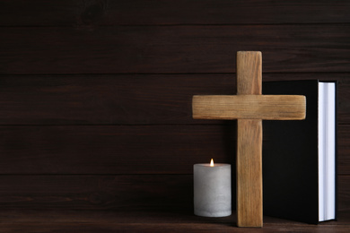 Cross, Bible and burning candle on wooden background, space for text. Christian religion