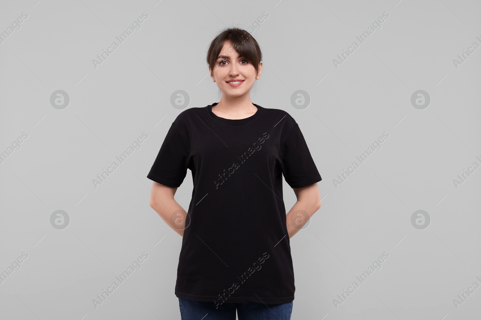 Photo of Smiling woman in stylish black t-shirt on light grey background