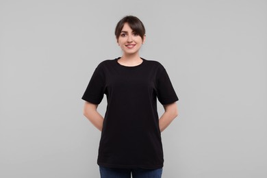 Smiling woman in stylish black t-shirt on light grey background