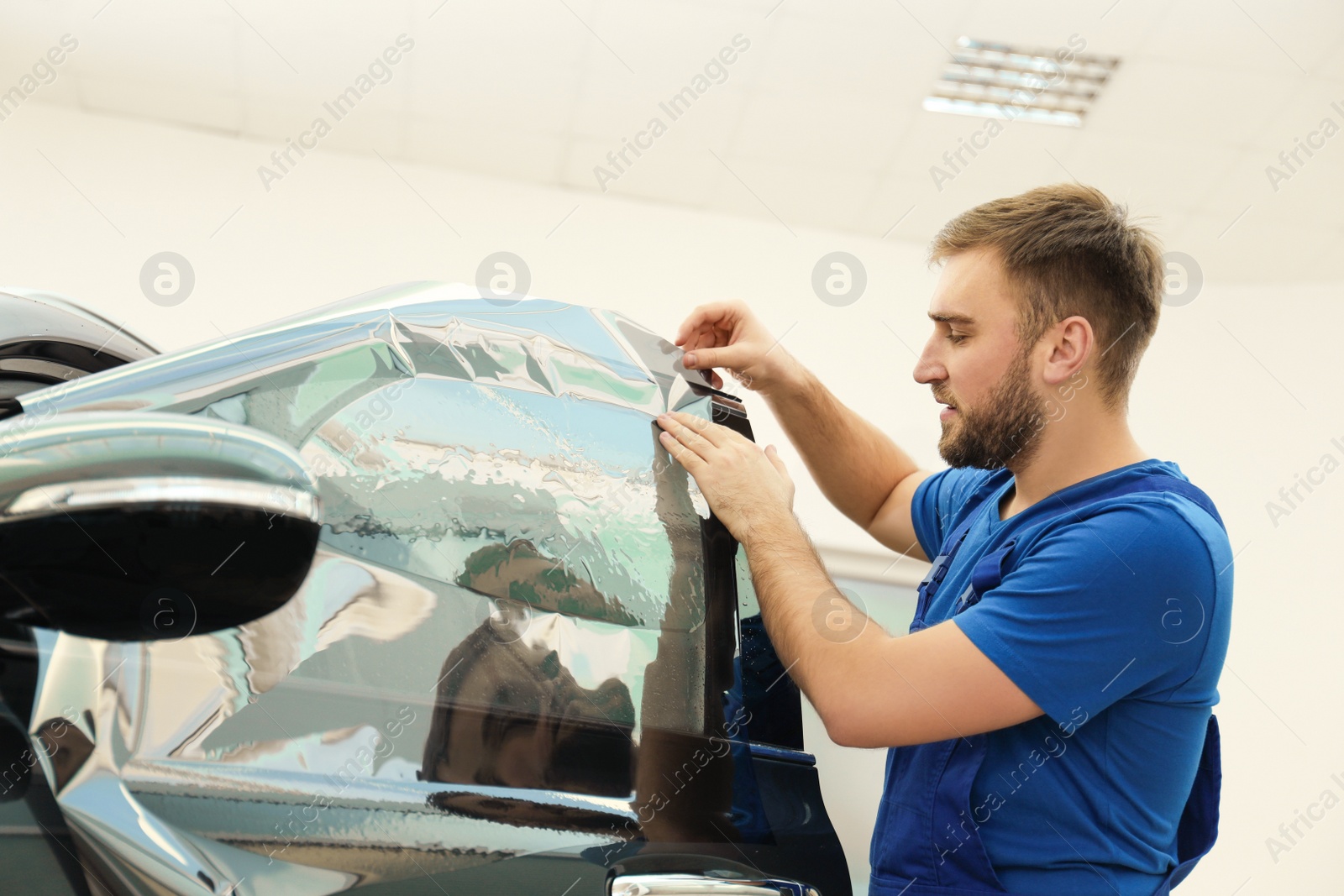 Photo of Worker tinting car window with foil in workshop