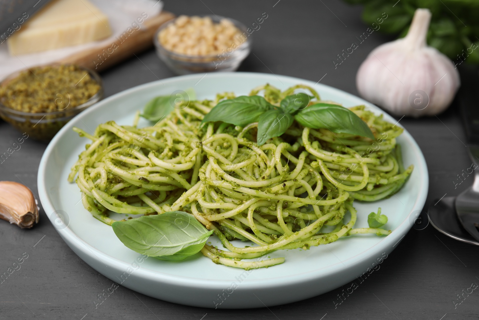 Photo of Delicious pasta with pesto sauce and basil on grey wooden table, closeup