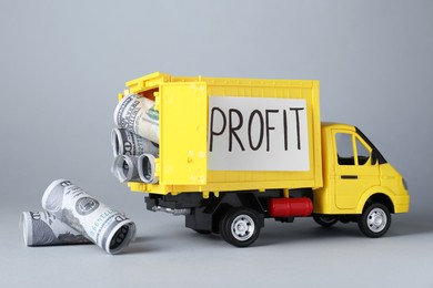 Photo of Economic profit. Toy truck with banknotes on light grey background