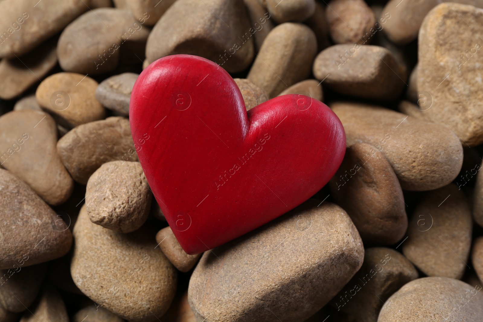 Photo of One red decorative heart on stones, closeup