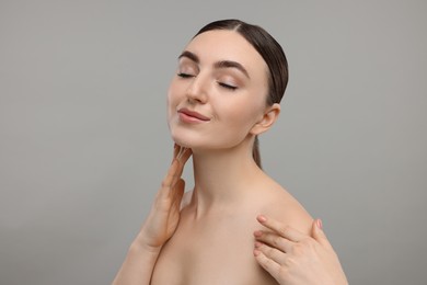 Photo of Beautiful woman touching her neck on grey background